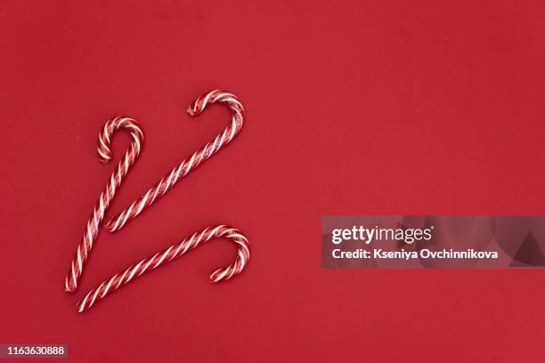 high angle shot of a group of christmas candy canes on a red background. the peppermint sticks run in all directions and out of the frame. - high sticking stock pictures, royalty-free photos & images