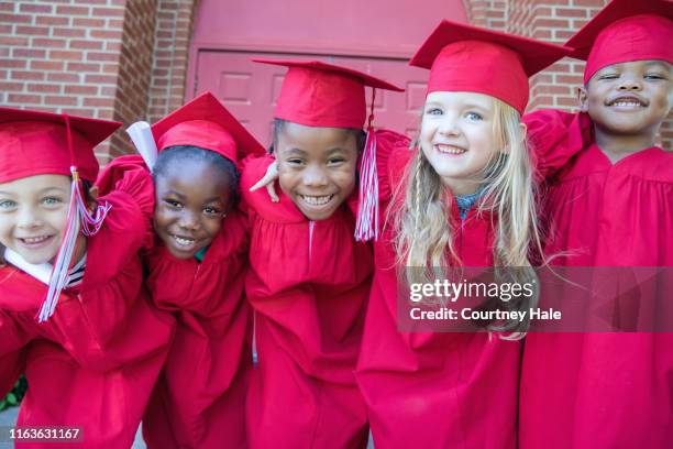 adorable kindergarten graduates smile and pose for photo together outside preschool - kindergarten graduation images stock pictures, royalty-free photos & images