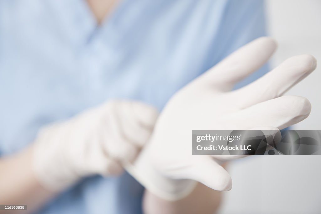 Close-up of female surgeon putting on gloves