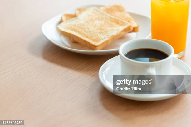 a white cup of coffee with toast bread in dish, orange juice on breakfast table. - orange juice glass white background stock-fotos und bilder