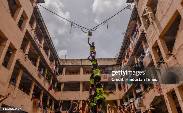 Hindu devotee breaks a dahi-handi suspended in the air atop a human pyramid during celebrations for the Janmashtami festival, which marks the birth...