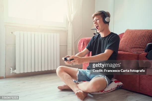 teenage boy  playing at video game - boy headphones stock-fotos und bilder
