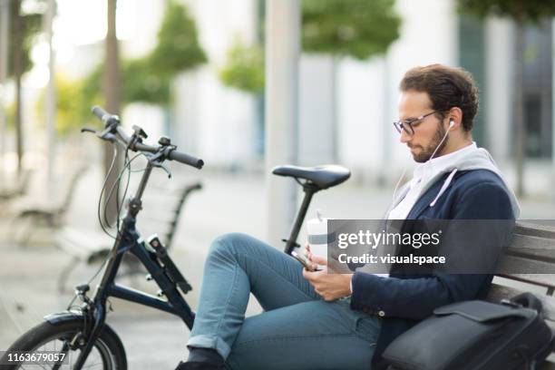 business pendler trinkt kaffee aus wiederverwendbaren kaffeetasse und hört podcast - business headphones stock-fotos und bilder