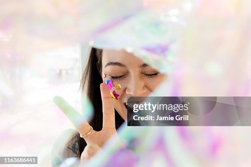 Woman with confetti on cheek making peace gesture Woman with confetti on cheek making peace gesture