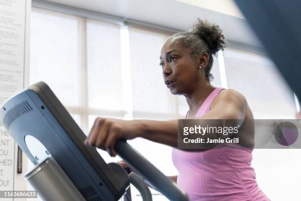 mature woman exercising on elliptical machine - women working out gym stock pictures, royalty-free photos & images