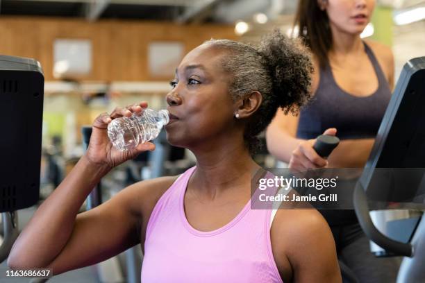 mature woman drinking water on break in gym - mature woman in water stock pictures, royalty-free photos & images