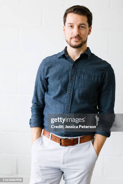 mid adult man wearing blue button down shirt - cinturón azul fotografías e imágenes de stock
