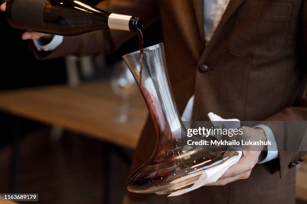 waiter pouring red wine into decanter - sommelier stockfoto's en -beelden