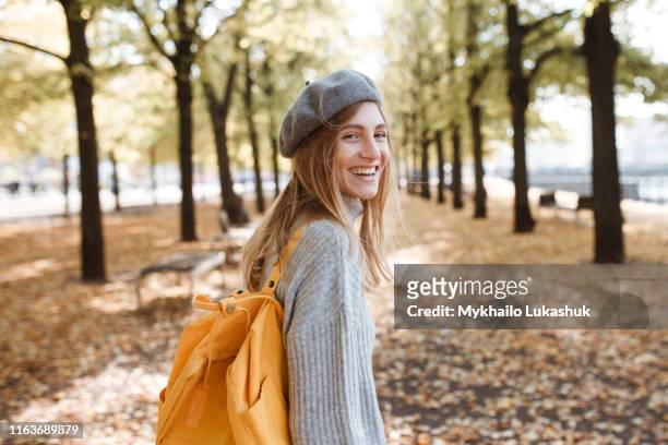 young woman with yellow backpack in park in berlin, germany - beret cap stock pictures, royalty-free photos & images