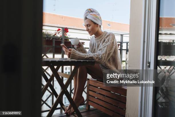 young woman drinking coffee on apartment balcony - berlin cafe fotografías e imágenes de stock