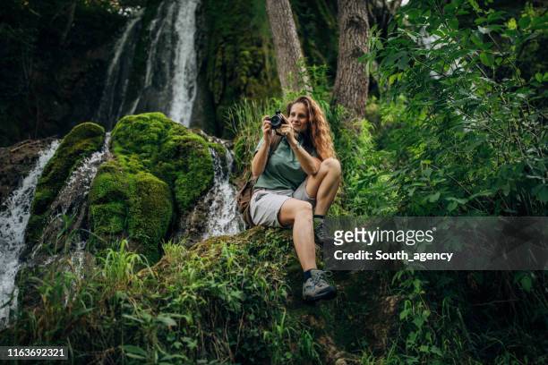 lady explorer sentada junto a la cascada - turismo ecológico fotografías e imágenes de stock