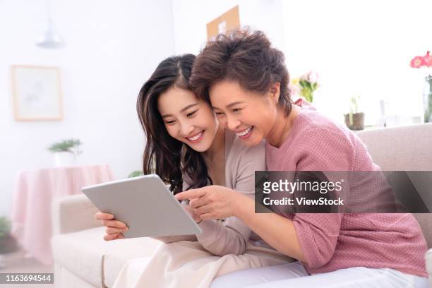 happy mother and daughter see tablets - chinese mothers day stockfoto's en -beelden