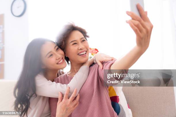 happy mother and daughter to use mobile phones - chinese mothers day stockfoto's en -beelden