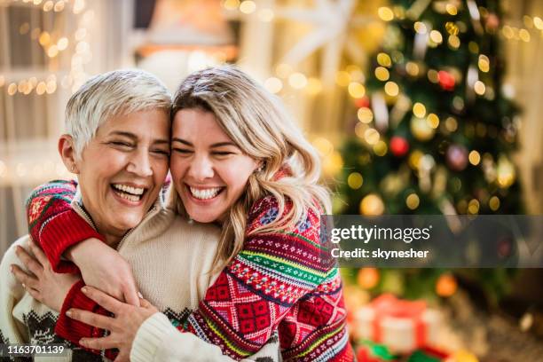 happy adult daughter embracing her senior mother on new year's day. - hug christmas stock pictures, royalty-free photos & images