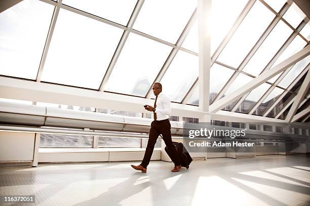 a businessman walking in an airport with luggage. - business people on the move stock pictures, royalty-free photos & images