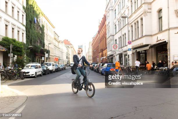electric bike commuter riding environment friendly bike through city - berlin summer stock pictures, royalty-free photos & images
