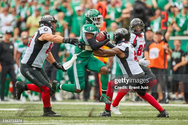 Derrick Moncrief of the Saskatchewan Roughriders runs with the ball through Nolan MacMillan and Dominique Davis of the Ottawa RedBlacks after...