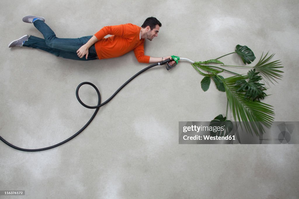 Young man holding industrial hose with plant