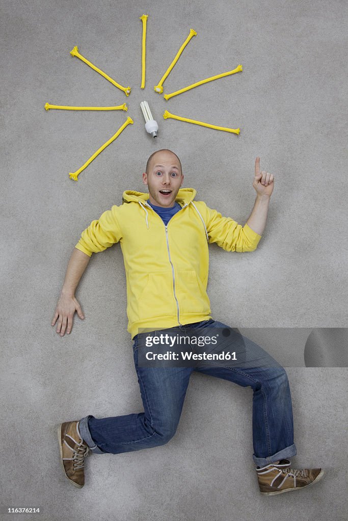 Young man pointing at electric bulb, portrait