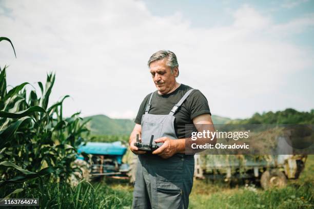 mature farmer flying a drone over a field - farmer drone stock pictures, royalty-free photos & images