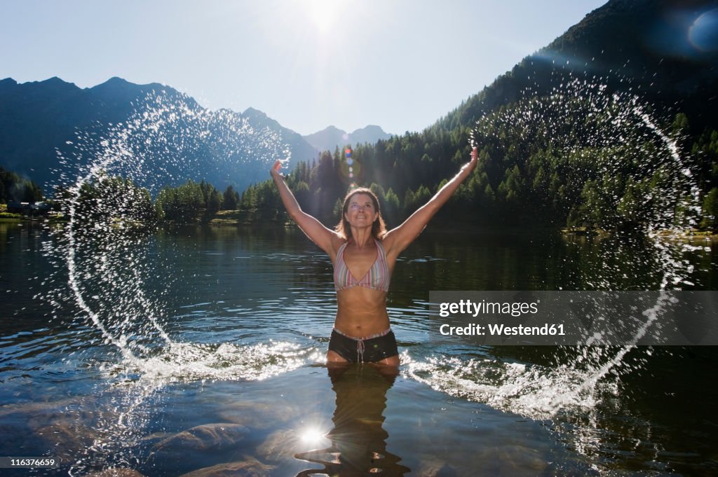 Austria, Styria, Mid adult woman standing in lake duisitzkar at schladming