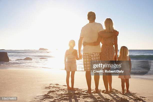 family on beach holding hands - four people holding hands stock pictures, royalty-free photos & images