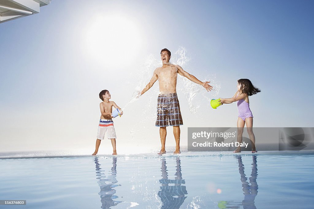 Children splashing water on man