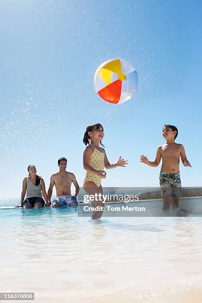 eltern beobachten kinder spielen mit ball im swimmingpool - wasserball stock-fotos und bilder