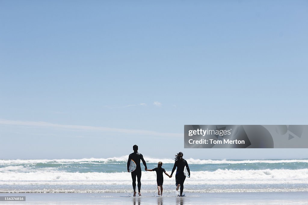 Parents and daughter with surfboard on beach