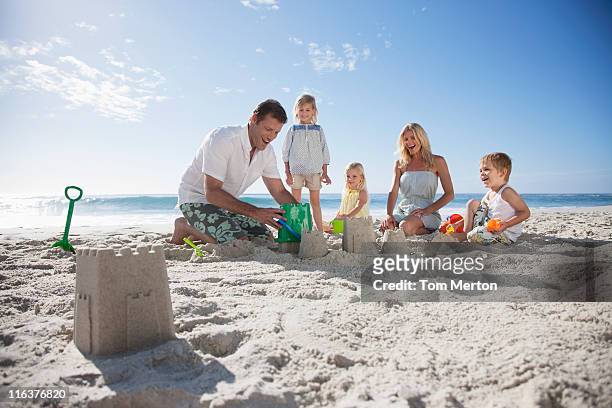 famiglia fare castelli di sabbia sulla spiaggia - five people foto e immagini stock
