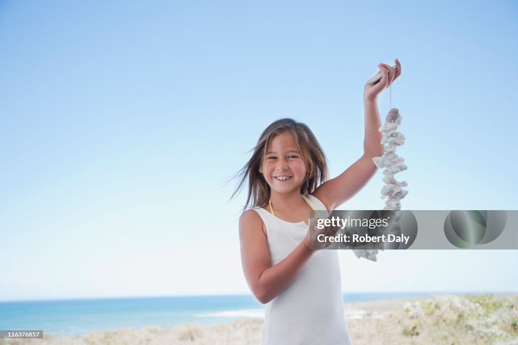 Girl holding shell necklace on beach