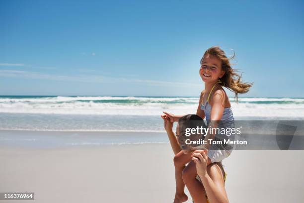 mother carrying daughter on shoulders - mother daughter beach stock pictures, royalty-free photos & images