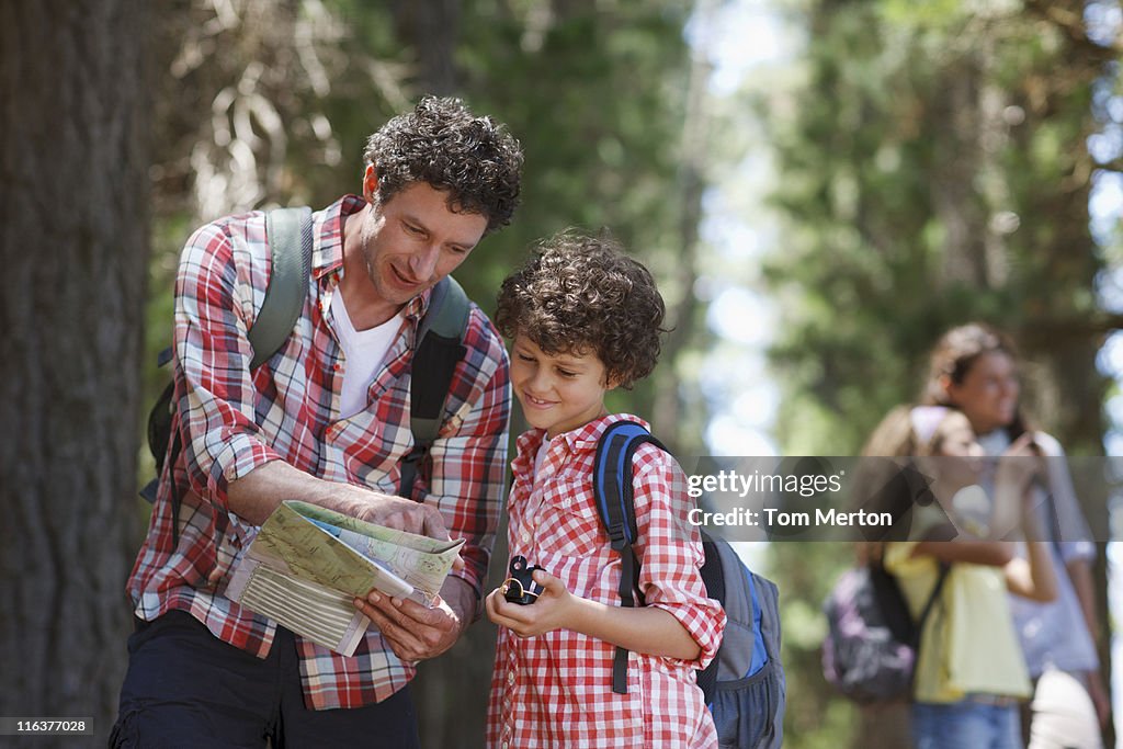 Father and son looking at map in woods