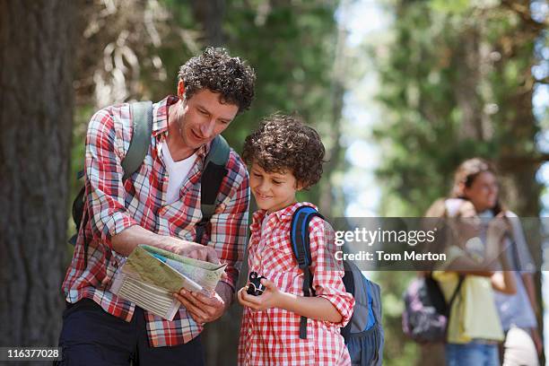 father and son looking at map in woods - hiking map stock pictures, royalty-free photos & images