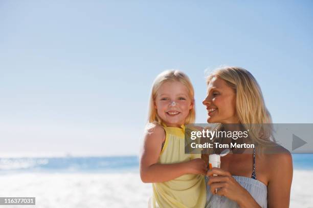 mother and daughter with sunscreen on beach - family 2010 stock pictures, royalty-free photos & images