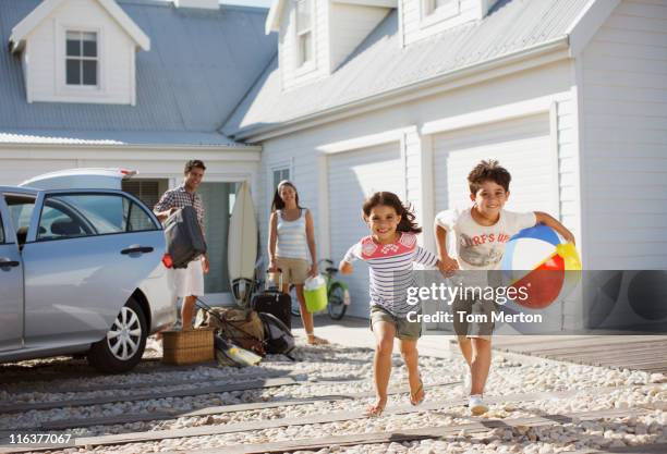 frère et soeur avec ballon de plage de course sur l'allée principale - maison-de-vacances photos et images de collection