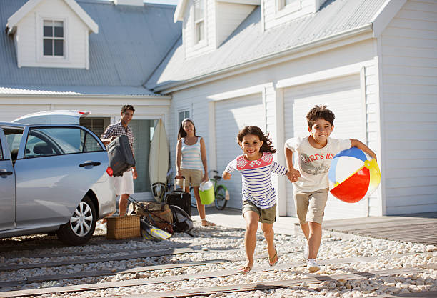 Brother and sister with beach ball running on driveway