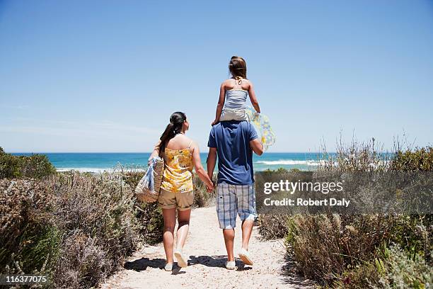 family walking on beach path toward ocean - beach bag stockfoto's en -beelden
