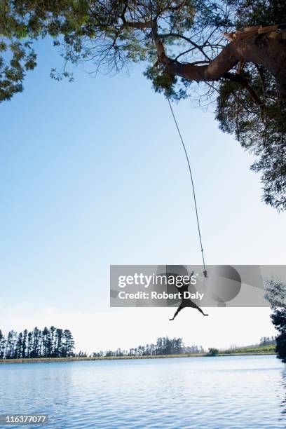 salto de hombre columpio de cuerda en lake - rope swing fotografías e imágenes de stock