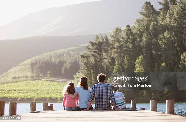 family sitting on lake dock - family lake stock pictures, royalty-free photos & images