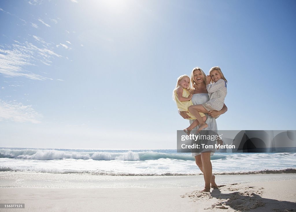 Mother holding daughters on beach