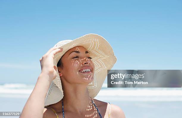 frau mit sonnenhut am strand - beach hut stock-fotos und bilder