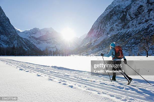 germany, bavaria, senior woman doing cross-country skiing with karwendal mountains in background - langlaufen stock-fotos und bilder