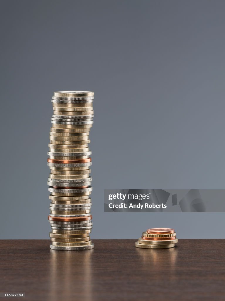 Tall stack of coins next to short stack of coins