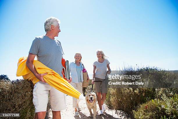 senior friends with dog walking on beach path - man met een groep vrouwen stockfoto's en -beelden