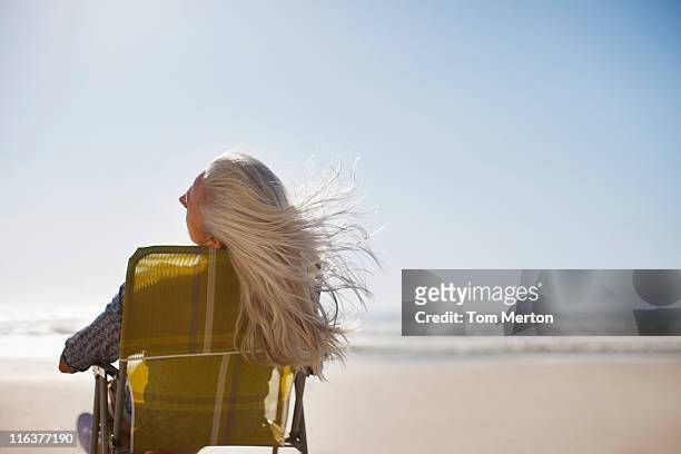 womans soffiatura dei capelli nel vento sulla spiaggia - capelli grigi foto e immagini stock