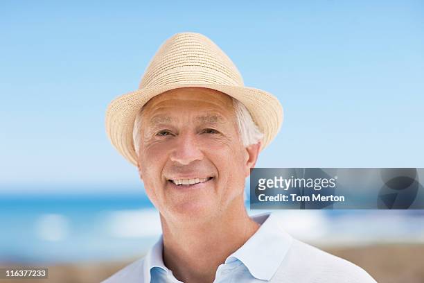 nahaufnahme eines lächelnden senior mann in hut - fedora stock-fotos und bilder