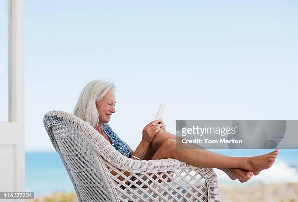 senior woman using digital tablet in chair - baby boomer stock pictures, royalty-free photos & images