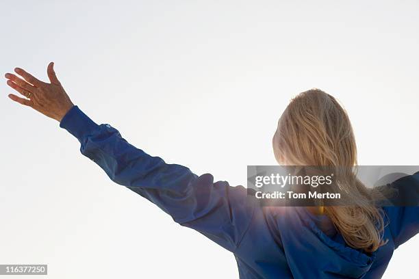 sole splende dietro donna con le braccia tese - arms outstretched foto e immagini stock