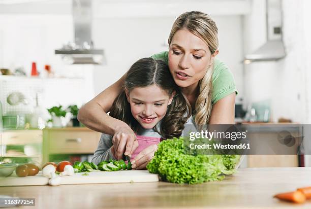 germany, cologne, mother and daughter preparing salad - generationen kochen stock-fotos und bilder